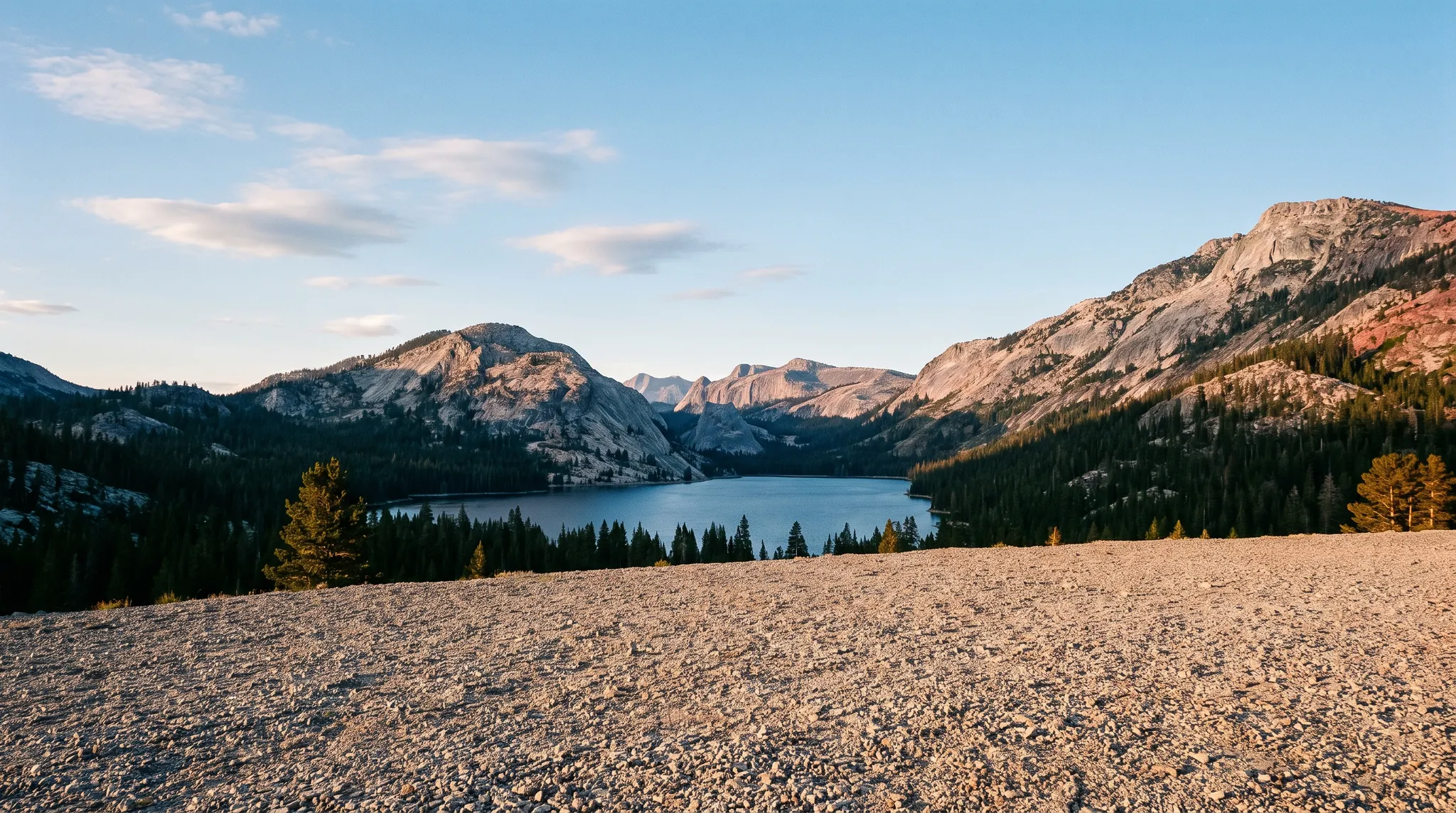 A white Class C motorhome on a gravel overlook above a mountain lake