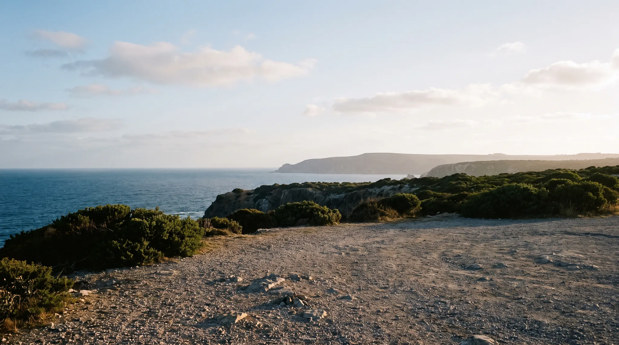 A white camper van on a gravel clifftop above the sea