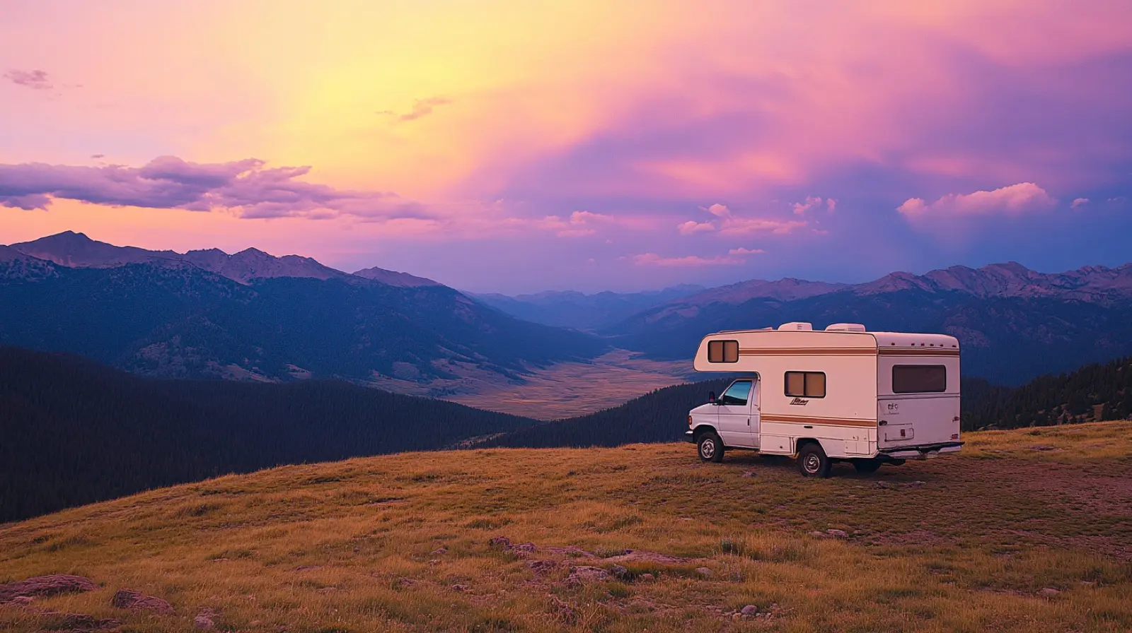 Small RV parked at remote mountain pass viewpoint at sunset