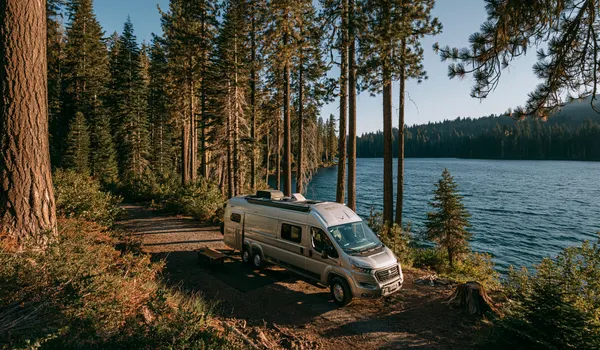 Camper van parked among tall pines beside an Oregon mountain lake